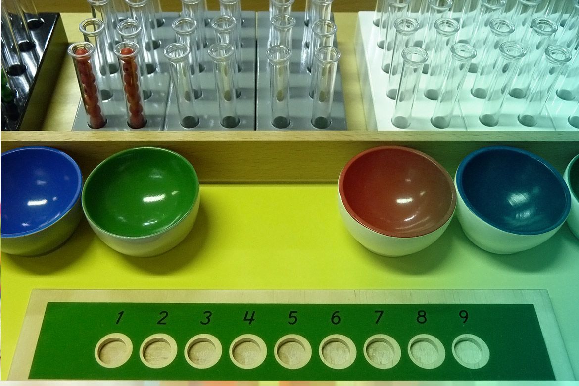 Montessori materials: test tubes, coloured bowls and a numbered tray
